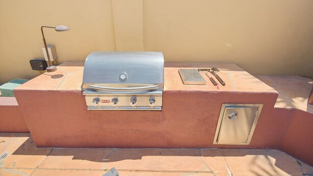 Ein Grill für den Außenbereich mit Bedienfeld, Thermometer und einem kleinen Tisch mit Lampe.