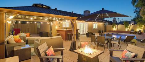 An outdoor patio area with seating, a pool, and string lights.