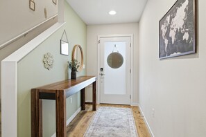 A hallway with a wooden console table, a hanging globe, a framed world map, and a door with a glass panel. - 2 Mi to Olympic National Park entrance: 4BR/2.5bath townhome in Port Angeles (Port Angeles)