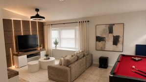 Een moderne woonkamer met een flatscreen televisie, een bank, een pooltafel en een groot abstract schilderij.
