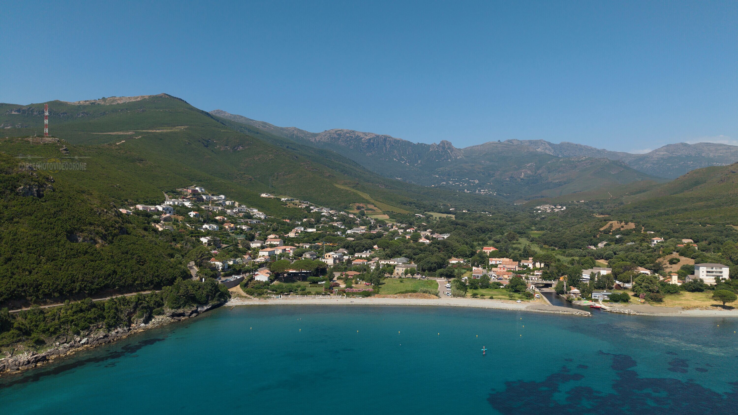A coastal town with a clear view of the sea and mountains in the background.