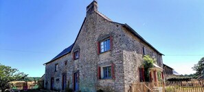 A stone building with a steep roof, multiple windows, and a wooden fence in the foreground. - A Stay in the Countryside - SAINTE COLOMBE (SAINTE COLOMBE)