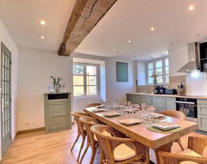 A dining area with a wooden table set for six, surrounded by wicker chairs. - A Stay in the Countryside - SAINTE COLOMBE (SAINTE COLOMBE)