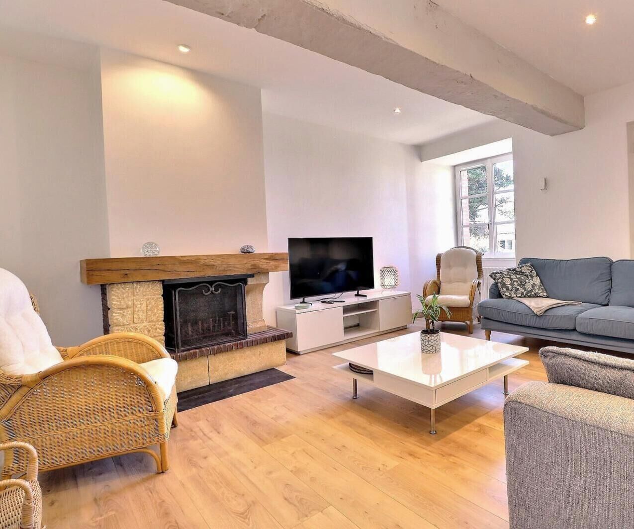 A living room with a fireplace, television, sofa, and wicker chairs.