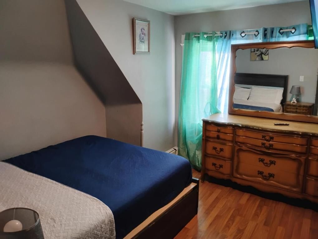 A bedroom with a bed, dresser, and a mirror.