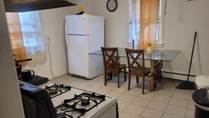 Une cuisine compacte équipée d’une cuisinière à gaz, d’un réfrigérateur blanc et d’une table à manger avec des chaises.