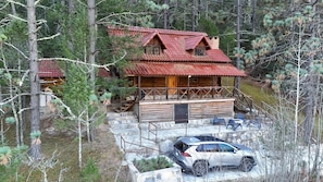 Une cabane avec un toit rouge, une façade en bois et une voiture garée devant.