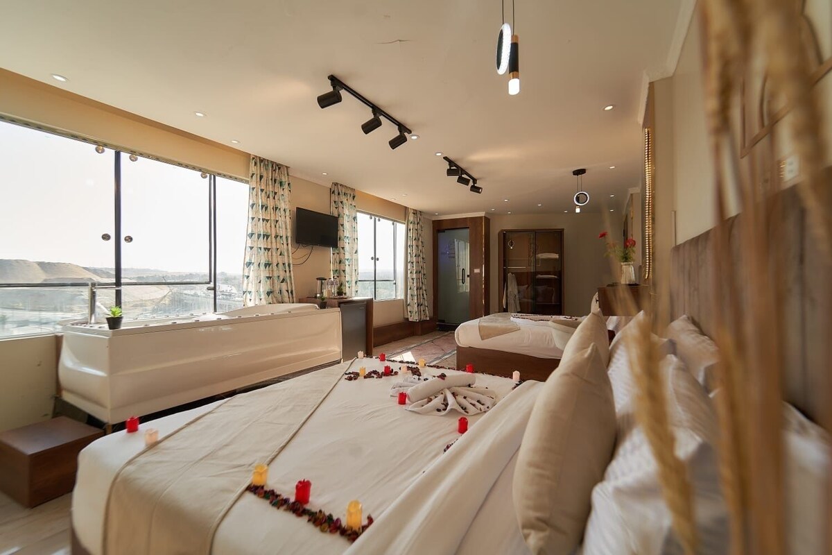 Ein Hotelzimmer mit einem großen Bett, einem Schreibtisch, einem Fernseher und Blick auf die Stadt.