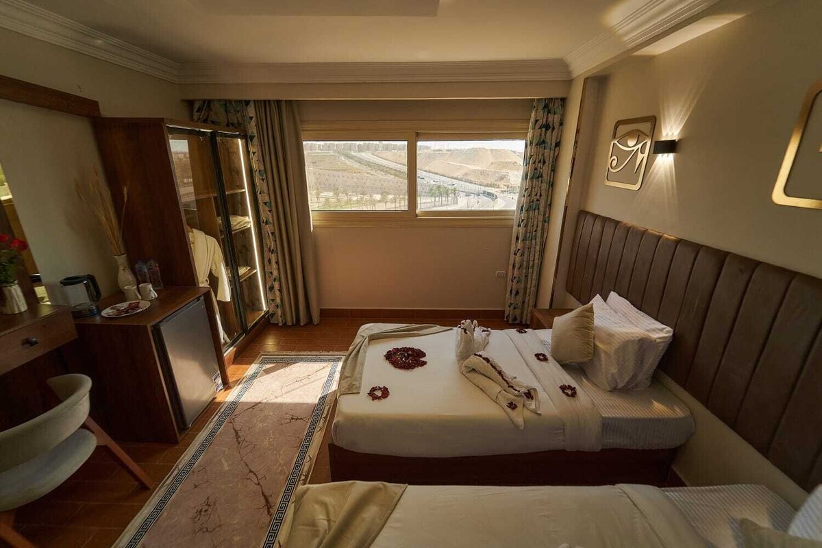 Ein Hotelzimmer mit Bett, Nachttisch, Spiegel, Kleiderschrank und Blick auf eine Wüstenlandschaft.