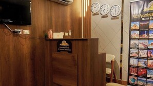A hotel reception area with a wooden reception desk, a flat-screen TV, an air conditioning unit, and a poster advertising the hotel's attractions. - Khofo Jacuzzi pyramids & GEM veiw (Giza Governorate)