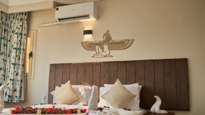 A hotel room with a bed, pillows, an air conditioning unit, and a wall decoration. - Khofo Jacuzzi pyramids & GEM veiw (Giza Governorate)