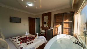 A bedroom with a bed, a large bathtub, a television, and a wardrobe. - Khofo Jacuzzi pyramids & GEM veiw (Giza Governorate)