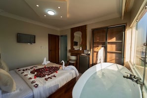 Ein Schlafzimmer mit einem Bett, einer Badewanne, einem Fernseher und einem Kleiderschrank.