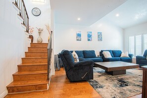 A staircase leading to a living area with a blue sofa set, a coffee table, and wall art. - The Blue Bungalow, Torrance CA (Torrance)