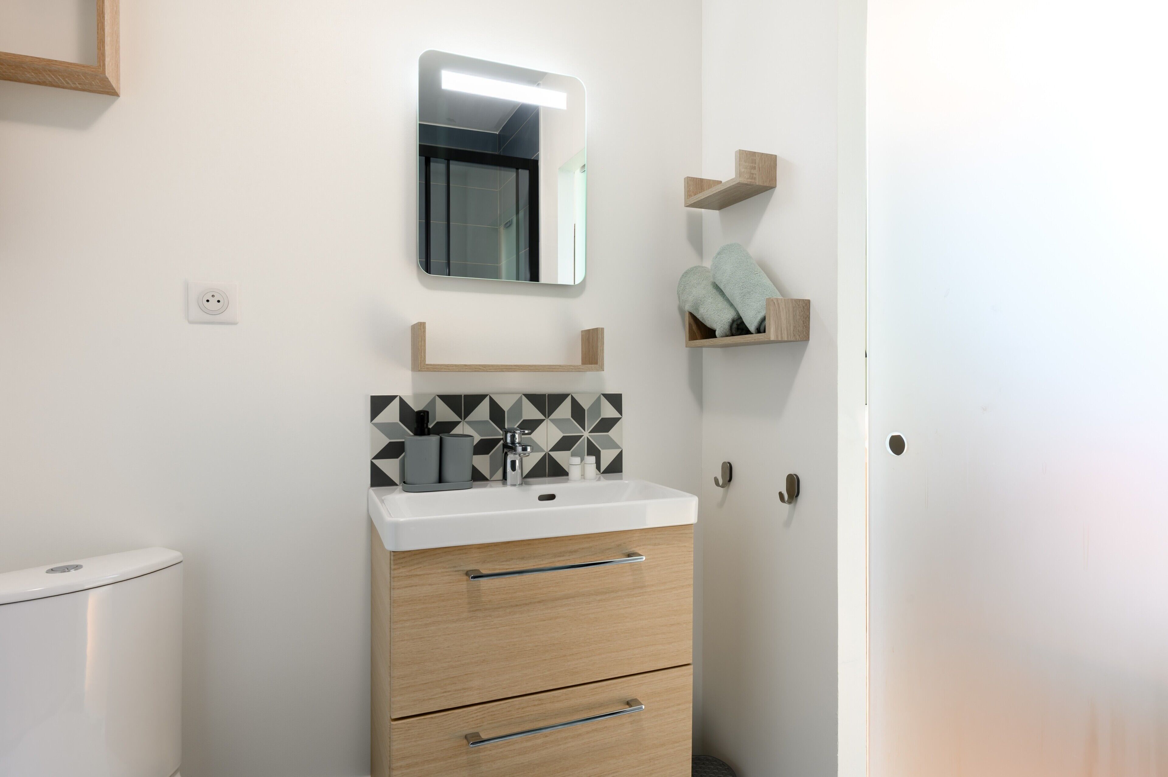 A bathroom with a white sink, a mirror, a toilet, and a towel rack.