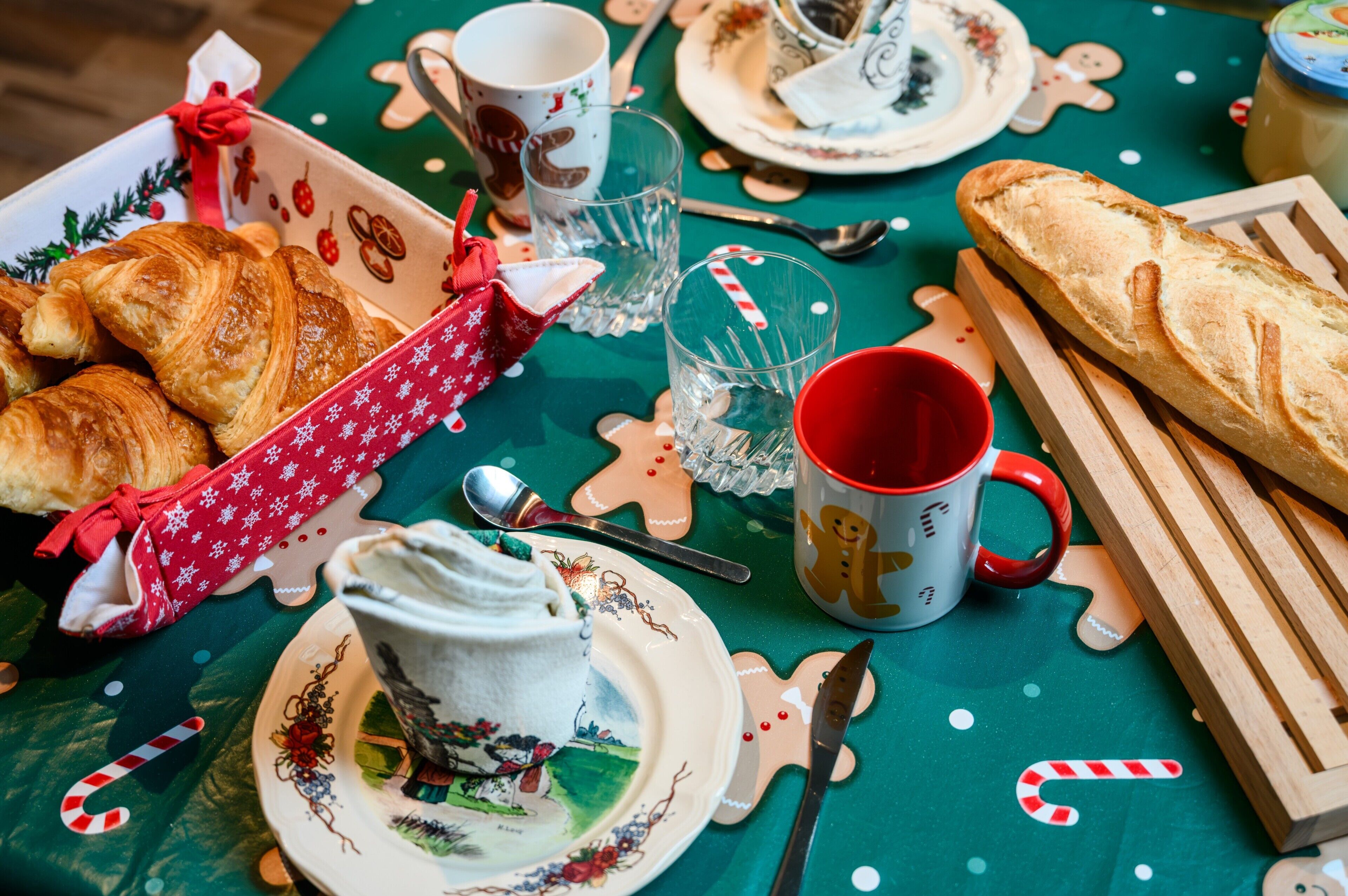A table set with croissants, a mug, a plate with a cup, and a wooden cutting board.