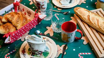 A table set with croissants, a mug, a plate with a cup, and a wooden cutting board.