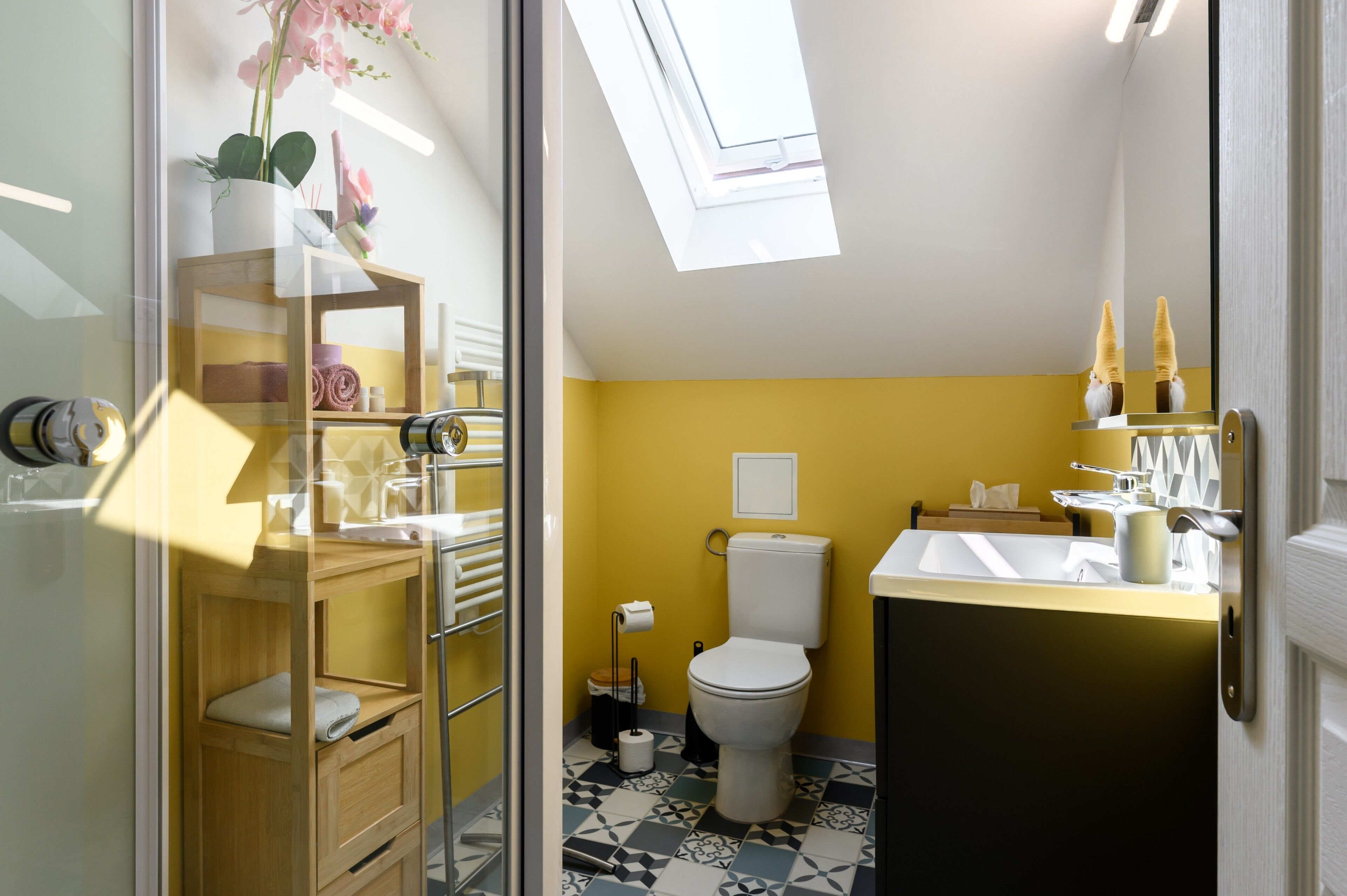 A bathroom with a toilet, sink, and a shelf with towels and toiletries.