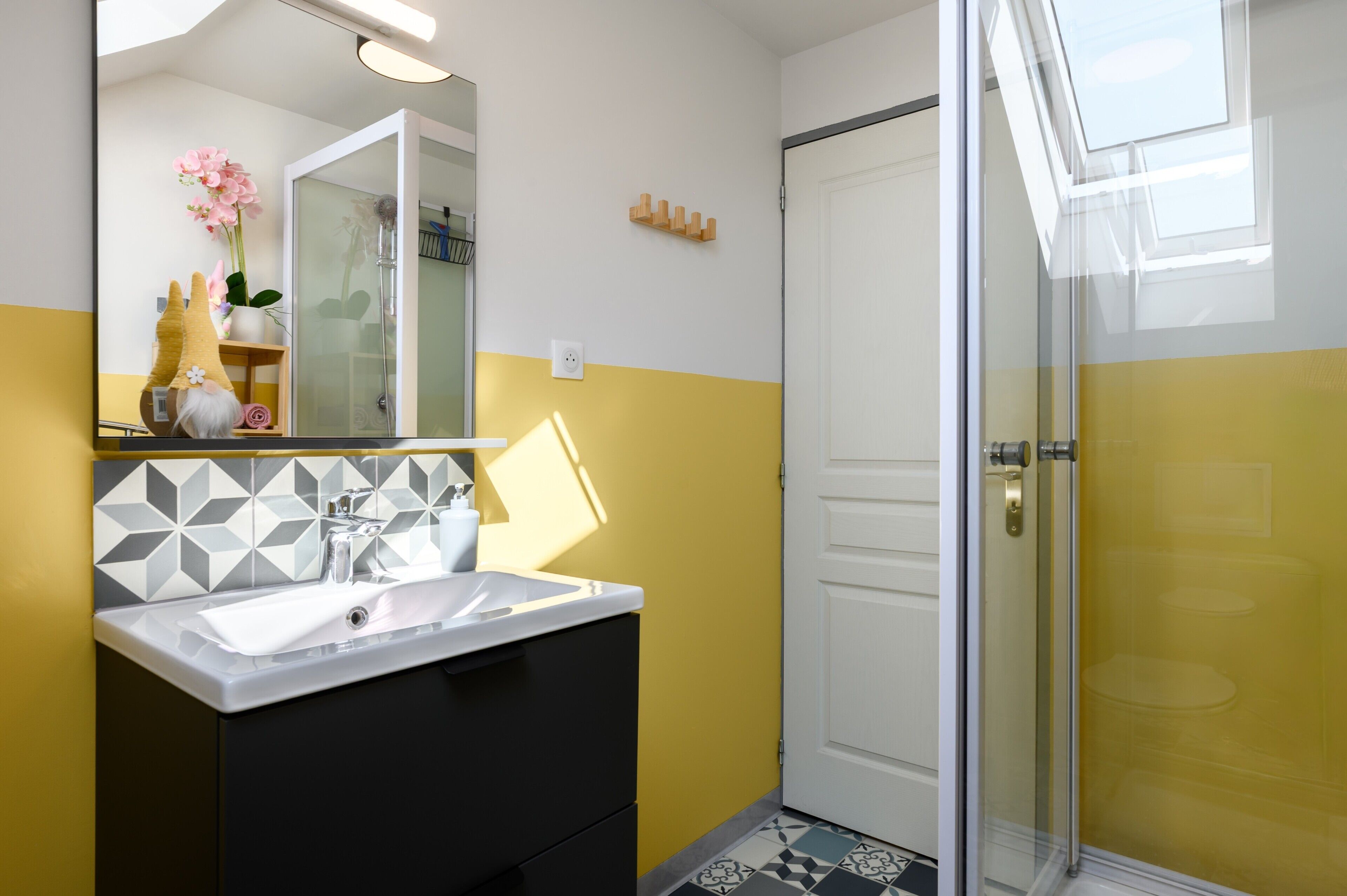 Un baño con lavamanos blanco, espejo y zona de ducha.