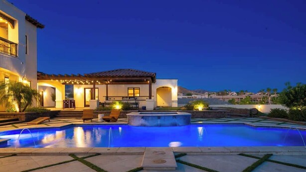 Piscina con hidromasaje, mobiliario de exterior y zona de patio techada.