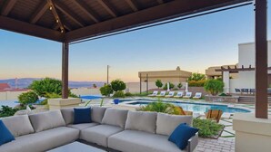 Un espacio exterior techado con piscina, sillones de descanso y un sofá.