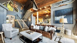 Ein geräumiges Wohnzimmer mit Treppe, einem großen Sofa, einem Couchtisch und einer Kristallleuchter.