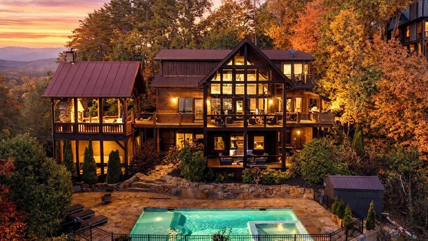 Ein großes, mehrstöckiges Holzhaus mit Schwimmbad, umgeben von Bäumen und Hügeln.
