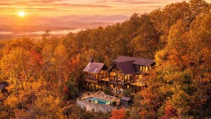 Eine große, mehrstöckige Holzhütte mit Pool, umgeben von dichtem Herbstlaub.