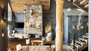 Ein rustikales Interieur mit Kamin aus Stein, Holzmöbeln und einer Treppe.