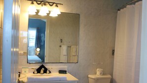 Une salle de bain avec un lavabo, un miroir et des toilettes.