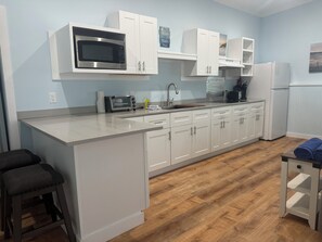 A kitchen with white cabinets, a microwave, a toaster, and a refrigerator. - BEACHSIDE TWO BEDROOM VILLA - PARTIAL OCEAN VIEW (Georgetown)
