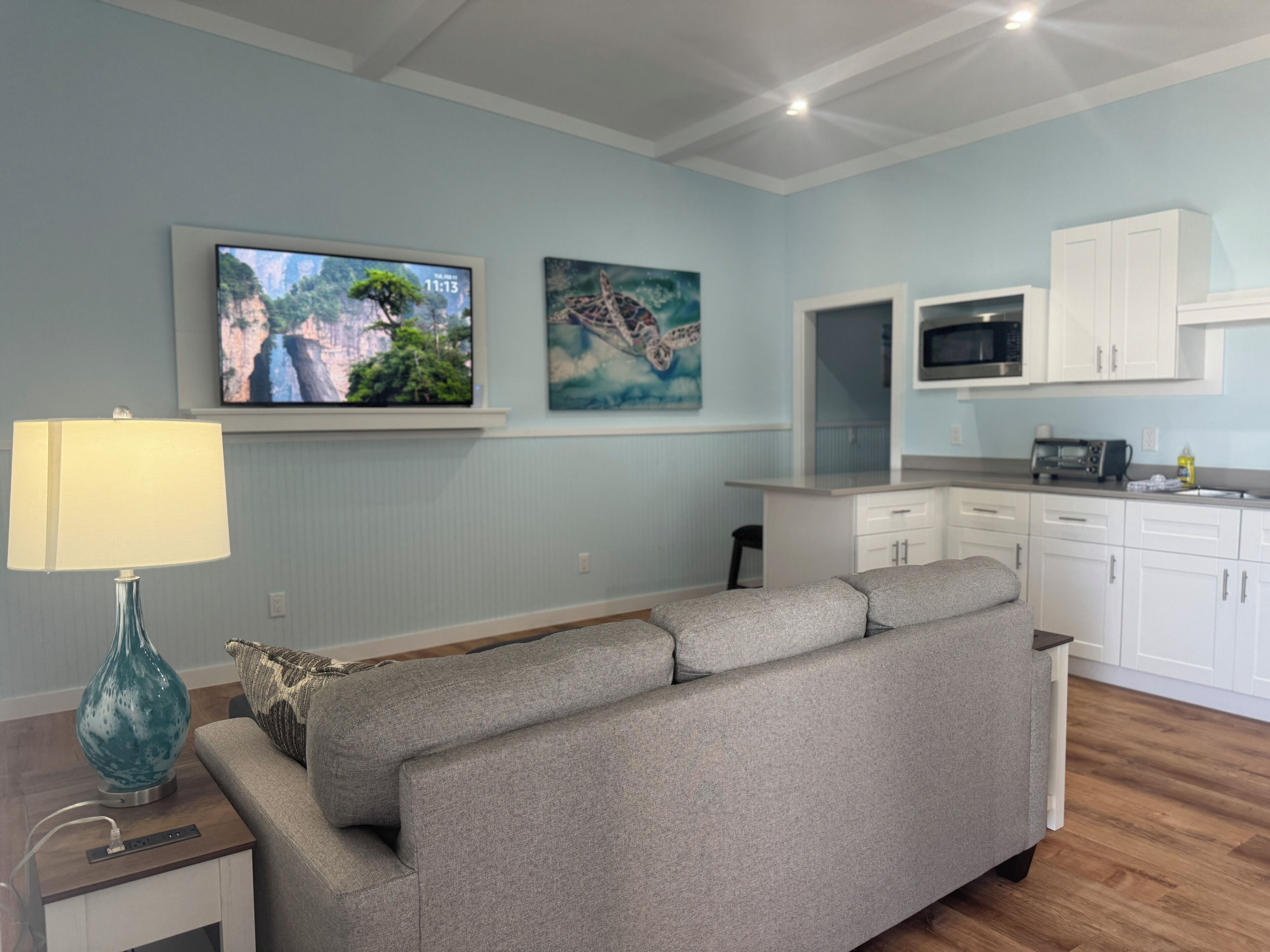 A living room with a sofa, a TV, and artwork on the wall.