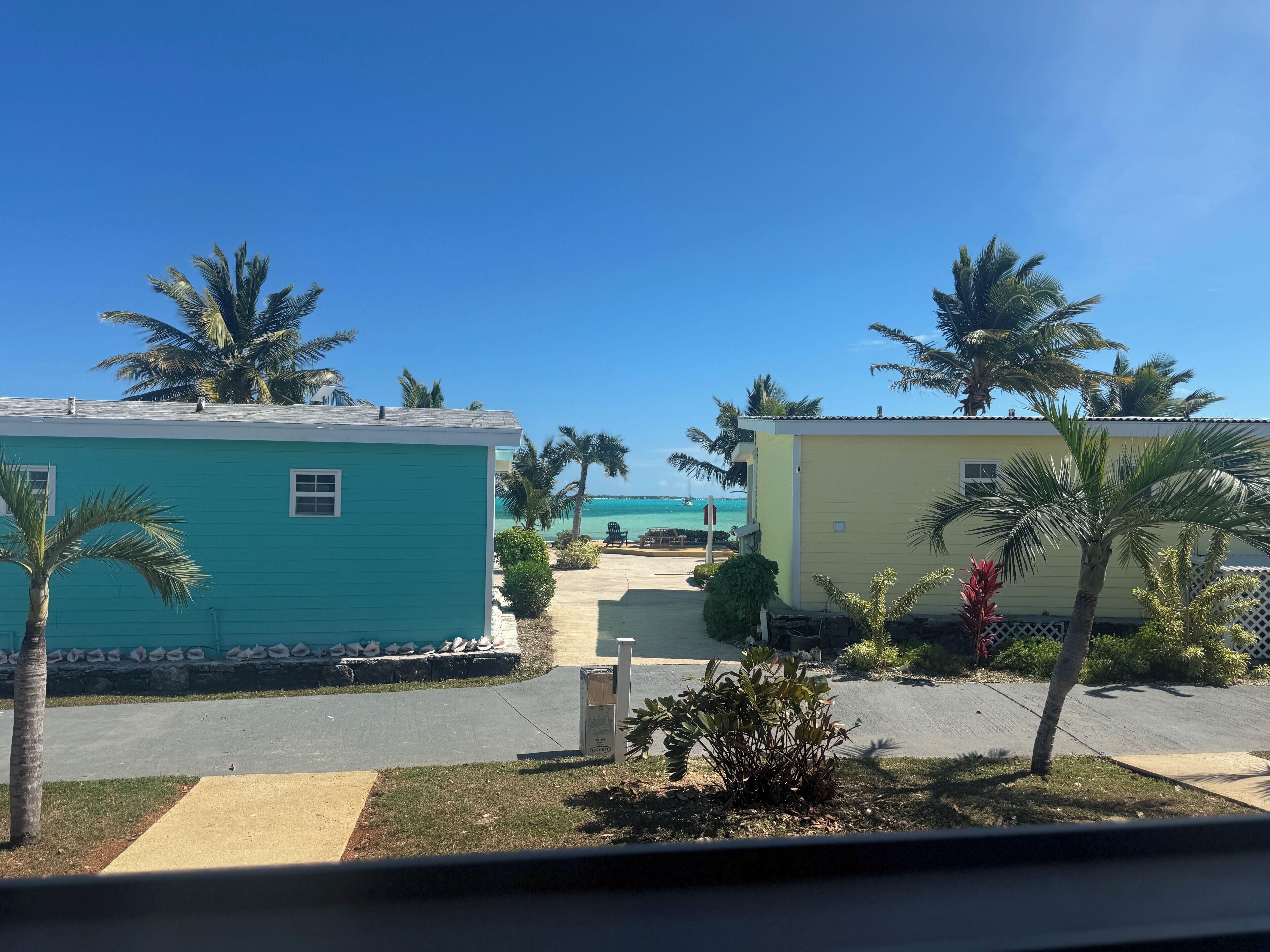 A view of a resort with two buildings, palm trees, and a clear blue sky.