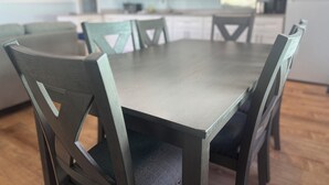 Une table à manger avec des chaises, un coin cuisine avec des placards et un tableau accroché au mur.