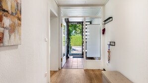 A hallway with a door leading outside, a bench, and a wall-mounted rack with items.