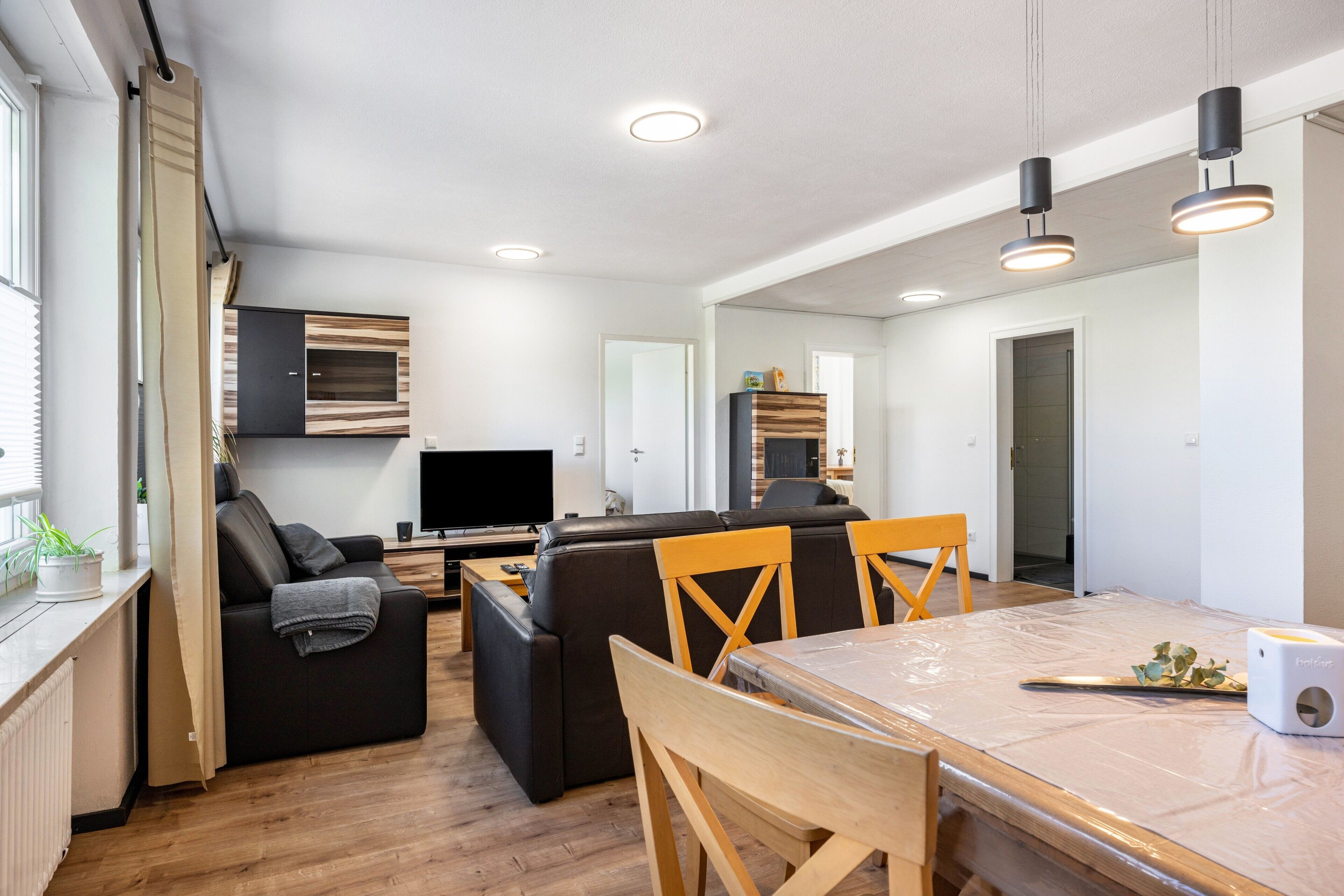 A modern living room with a sofa, a dining table, and a TV.