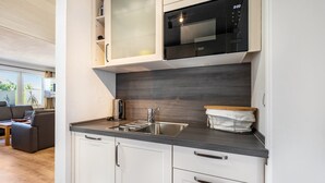 A modern kitchen with a built-in microwave, stainless steel sink, and white cabinetry.
