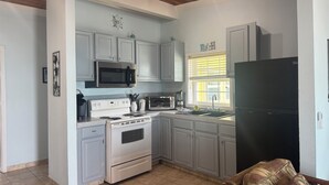 A kitchen with white cabinets, a black refrigerator, a microwave, a stove, and a sink. - BEACHSIDE TWO BEDROOM VILLA - OCEANVIEW (Georgetown)