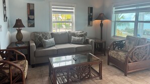 A living room with a sofa, armchairs, a glass coffee table, and a lamp. - BEACHSIDE TWO BEDROOM VILLA - OCEANVIEW (Georgetown)