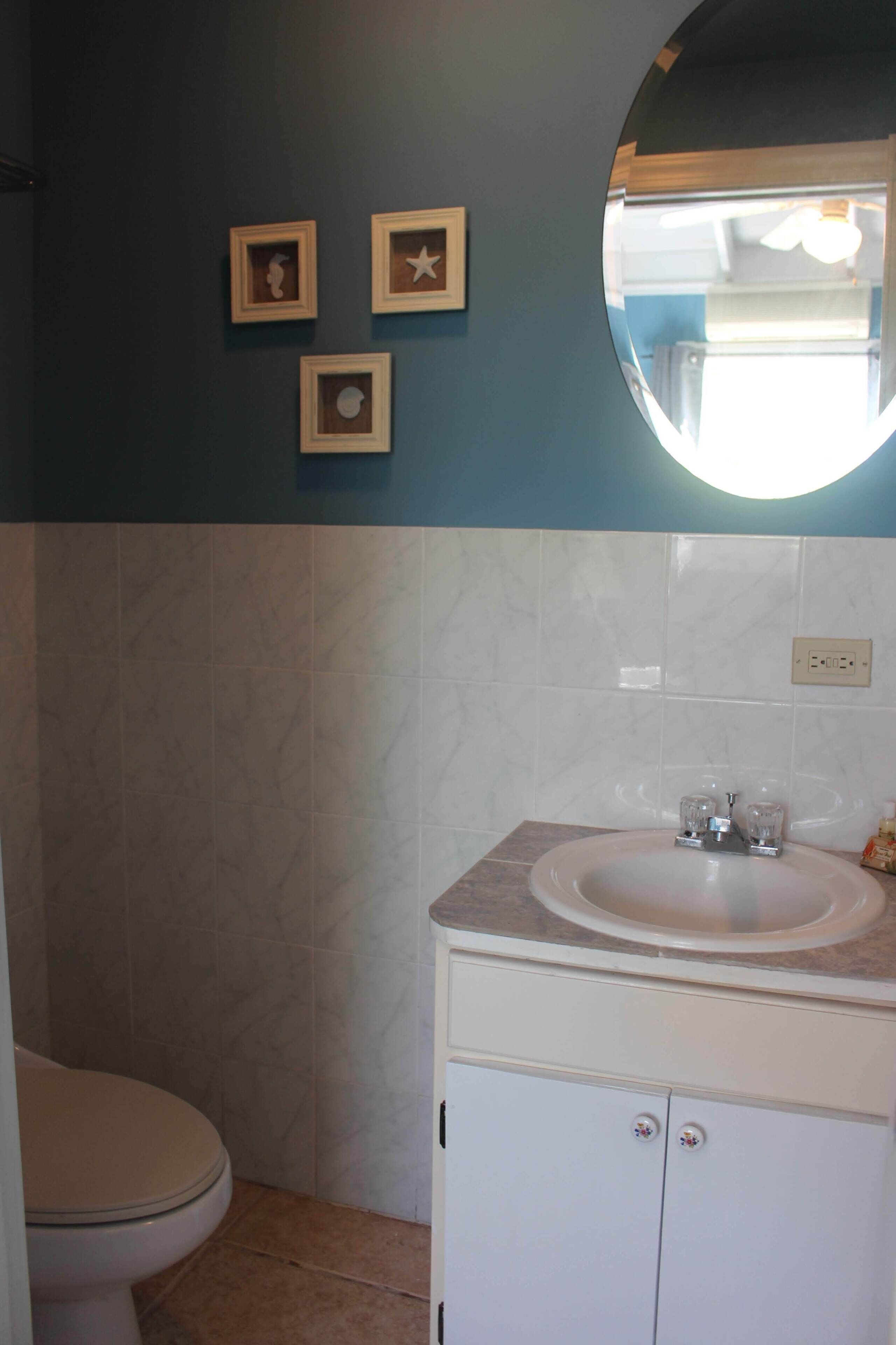 Une salle de bain avec des toilettes, un lavabo et un miroir.