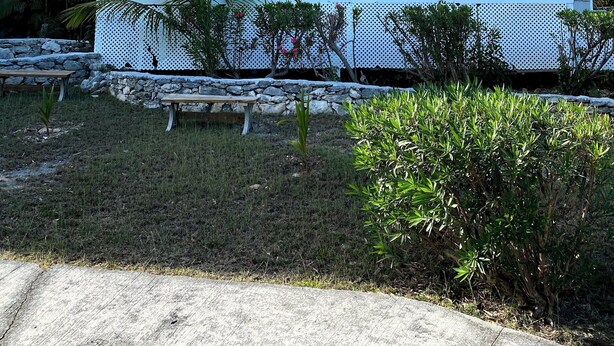 A two-story building with balconies, a stone wall, and a small garden area. - HILLSIDE TWO BEDROOM VILLA - OCEANVIEW (Georgetown)