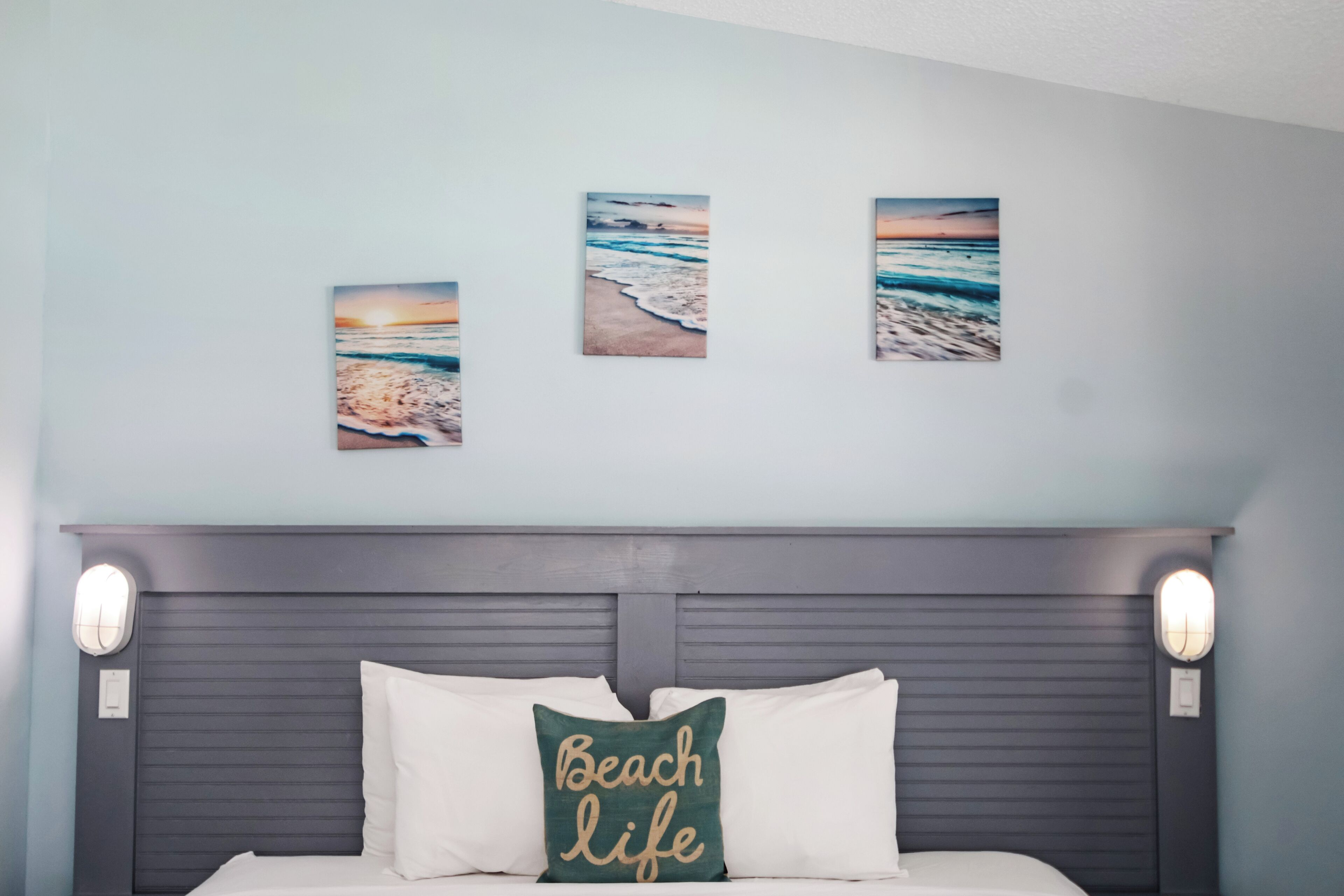 A bedroom with a bed, a headboard, and three framed pictures on the wall.