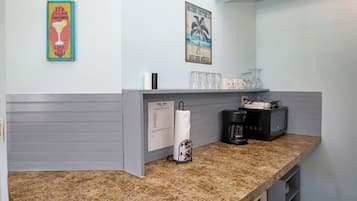 A kitchen counter with a coffee maker, a paper towel holder, and a glass rack.