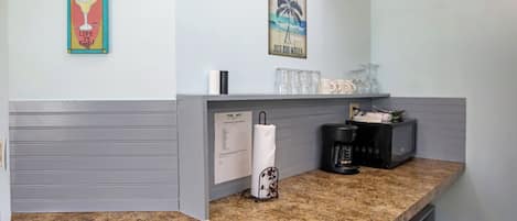 A kitchen counter with a coffee maker, a paper towel holder, and a glass rack.
