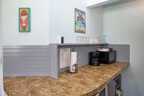 Un piano di lavoro in cucina con una macchina da caffè, un porta asciugamani di carta e un portabicchieri.