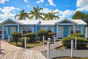 Eine Reihe blauer Gebäude mit weißen Verzierungen, ein Holzdeck und Palmen.