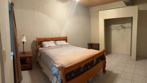 A bedroom with a wooden bed, a bedside table, a lamp, and a wardrobe. - 9-Bedroom Ocean View Home in Vista Marina for Large Groups (Vista Marina)