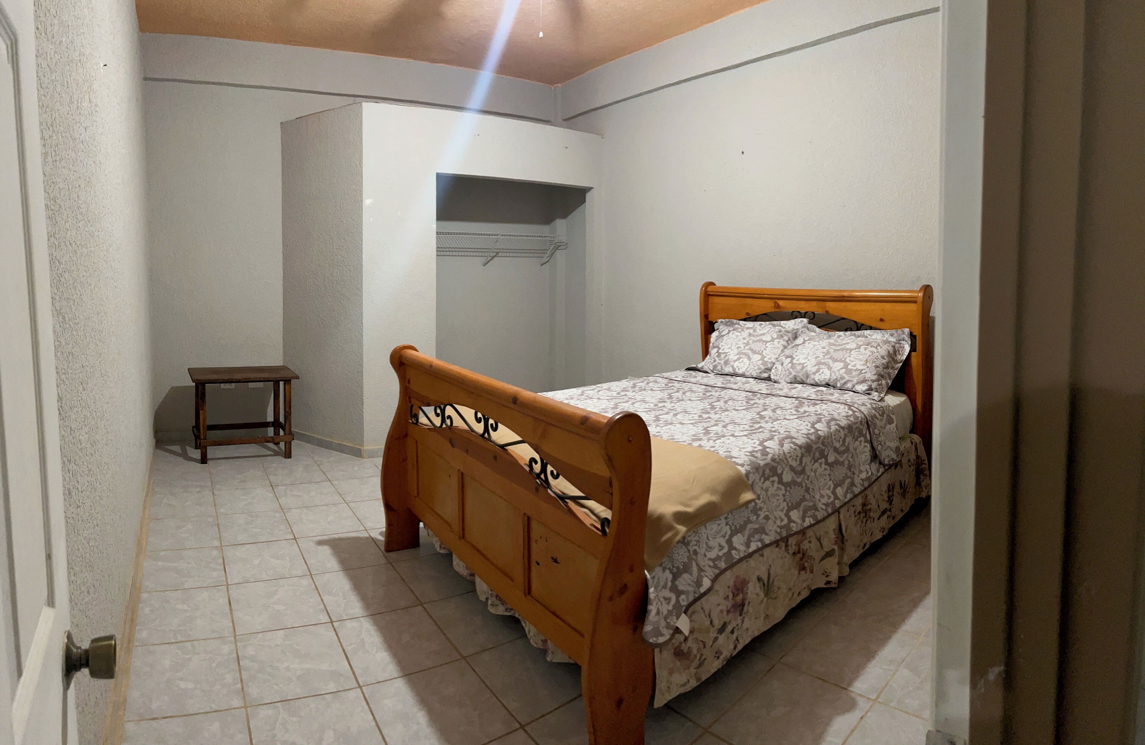 Ein Schlafzimmer mit einem hölzernen Bett, einem kleinen Nachttisch und einem Kleiderschrank.