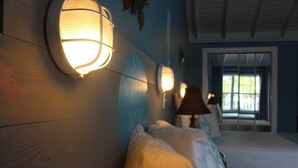A bedroom with a bed, bedside lamps, a window, and a door. - BEACHSIDE ONE BEDROOM COTTAGE - OCEANVIEW (Georgetown)