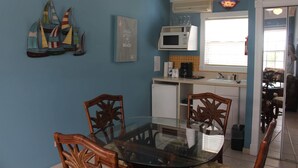 A dining area with a glass table, wooden chairs, a microwave, and a small refrigerator. - BEACHSIDE ONE BEDROOM COTTAGE - OCEANVIEW (Georgetown)